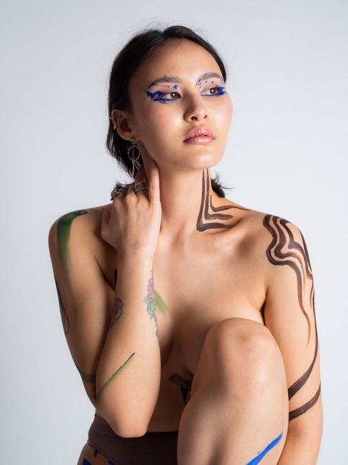 Free Expressive portrait of a woman with vibrant body paint and makeup, posing in a studio. Stock Photo