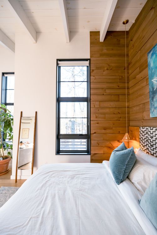 Free A stylish bedroom featuring a wood accent wall, minimalist decor, and ample natural light. Stock Photo