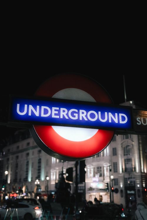 Free Illuminated London Underground sign glowing at night downtown. Stock Photo