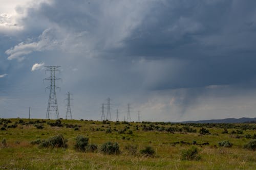 Free 在白雲和藍天下的綠色田野上的灰色電崗 Stock Photo