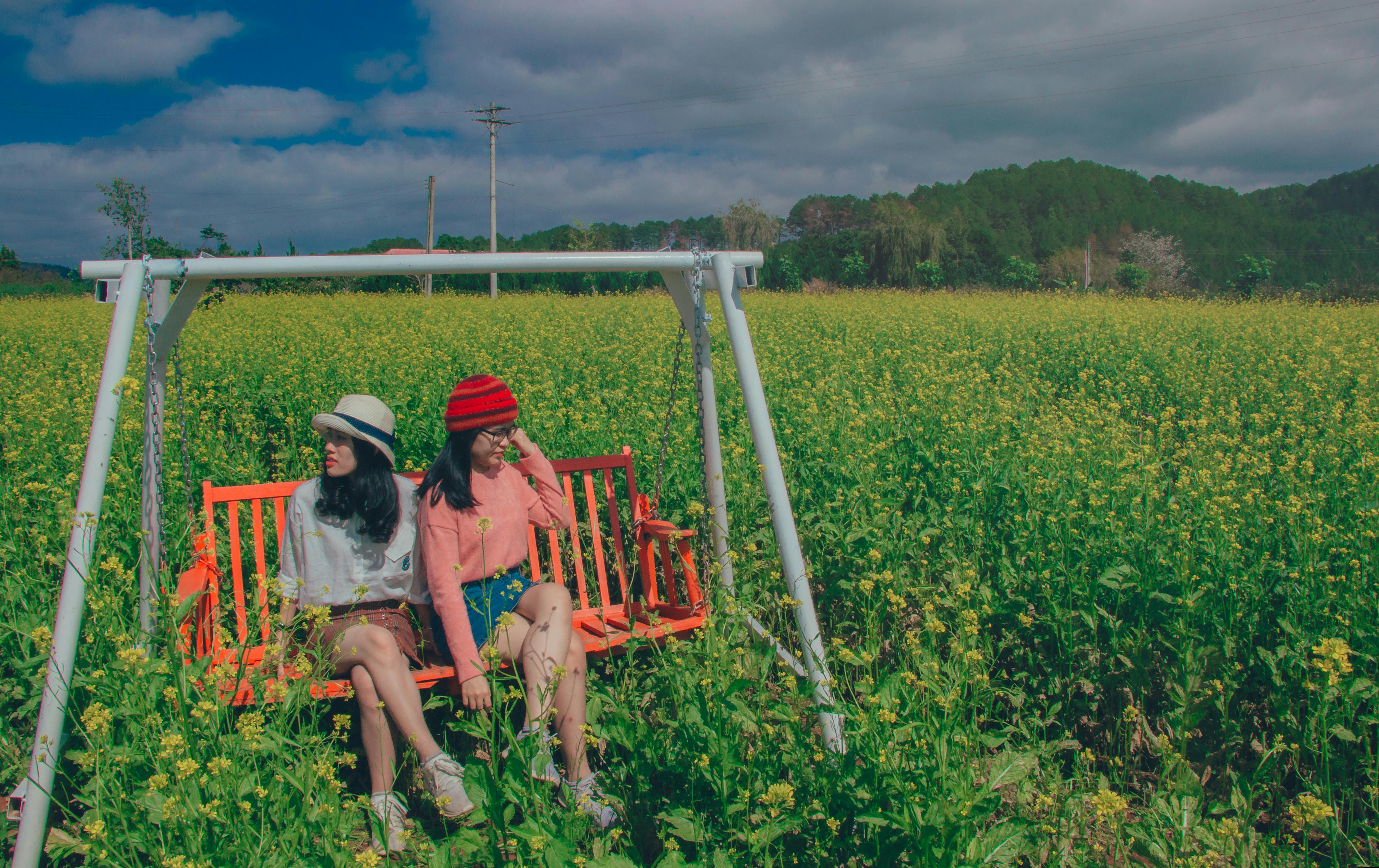 two women sitting on swing bench