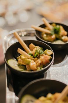 Elegant presentation of avocado and salmon salad garnished with herbs in a black bowl.