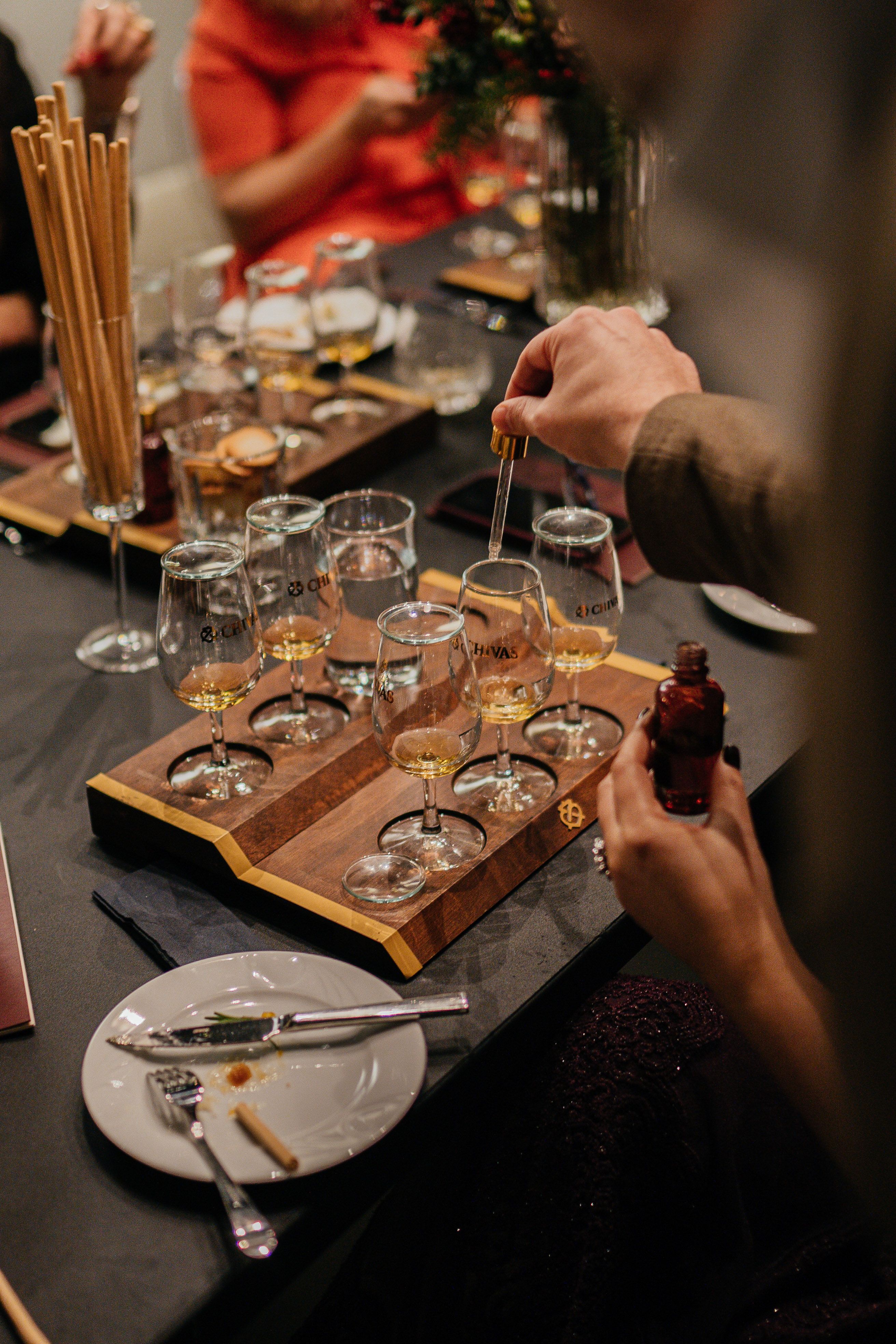 A group enjoying a sophisticated whiskey tasting event with beautifully arranged glasses and snacks.
