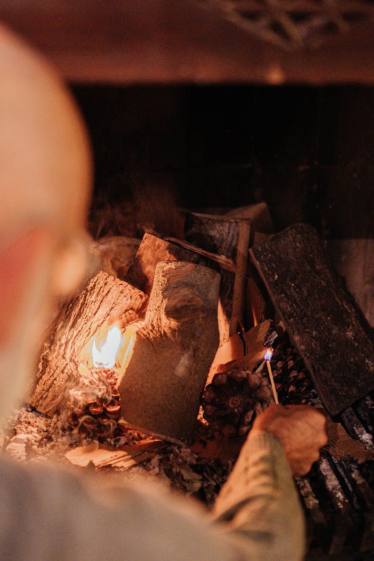 Man Lighting Firewood In The Fireplace