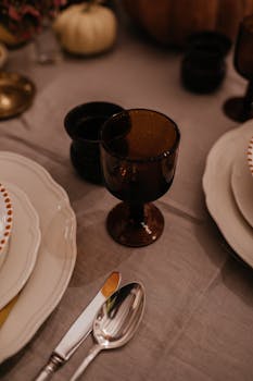 Close-up of an autumn dining table setup featuring amber glasses and elegant tableware.