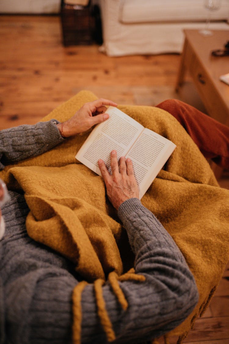 Person Reading Book Under Blanket