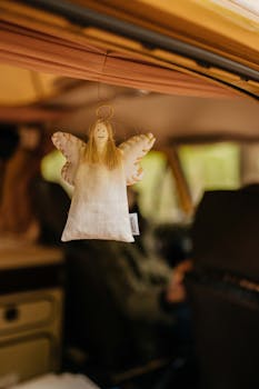A charming angel keychain hanging inside a retro caravan with a cozy atmosphere.