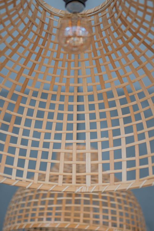 Free Close-up shot of a modern woven bamboo chandelier with a visible light bulb, showcasing intricate craftsmanship. Stock Photo