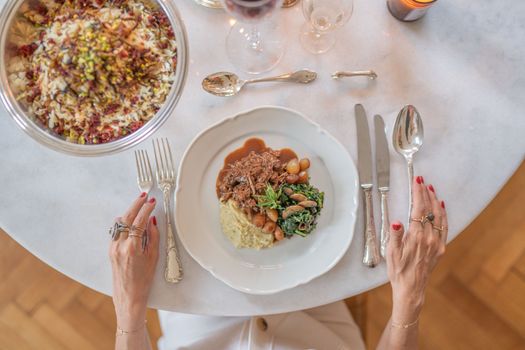 Fine dining setup viewed from above featuring a gourmet meal, wine, and elegant cutlery on a modern table.