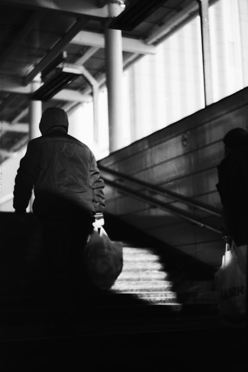 Grayscale Photo of a Person Going Up the Stairs  