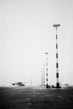 Black and white photo of a helicopter near airport masts on a winter day.