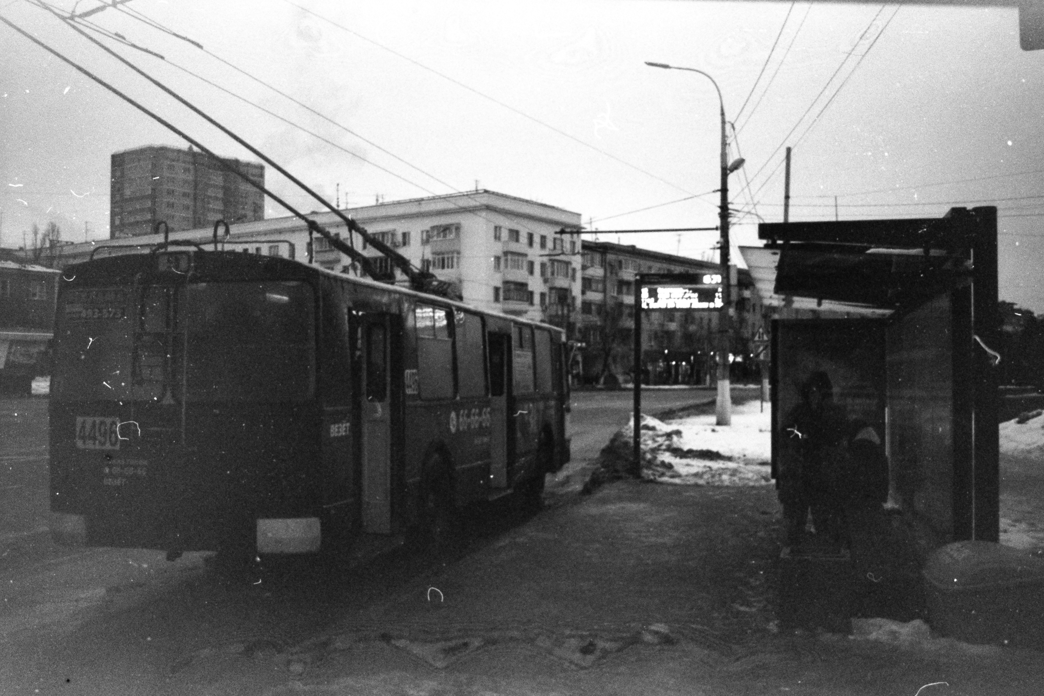 Black and white photo of a city bus at a bus stop in winter.