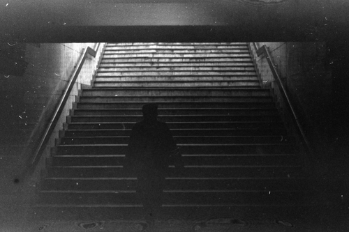 Free A silhouette of a person ascending stairs in a gritty urban underground setting in black and white. Stock Photo