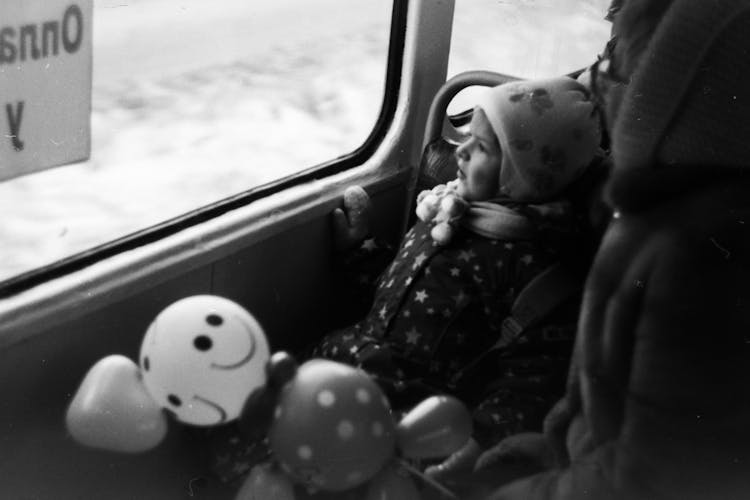 Grayscale Photo Of A Child Looking Out Of A Bus Window