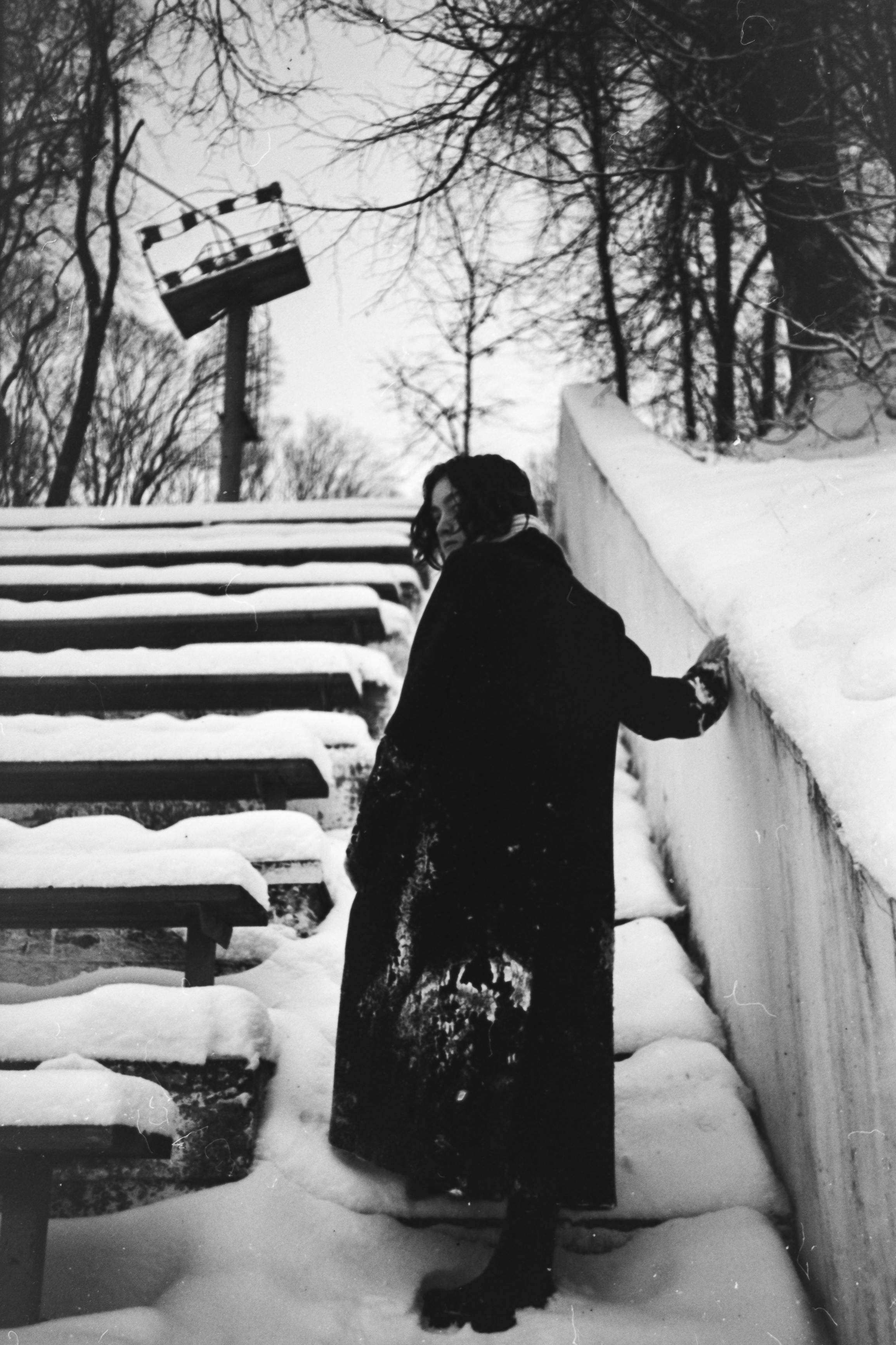 Free Black and white photo of a woman walking in a snowy amphitheater in winter. Stock Photo