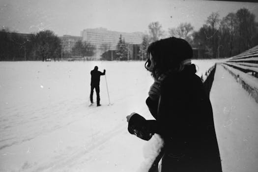 A vintage black and white photo of skiing in winter with two people in a snowy landscape.