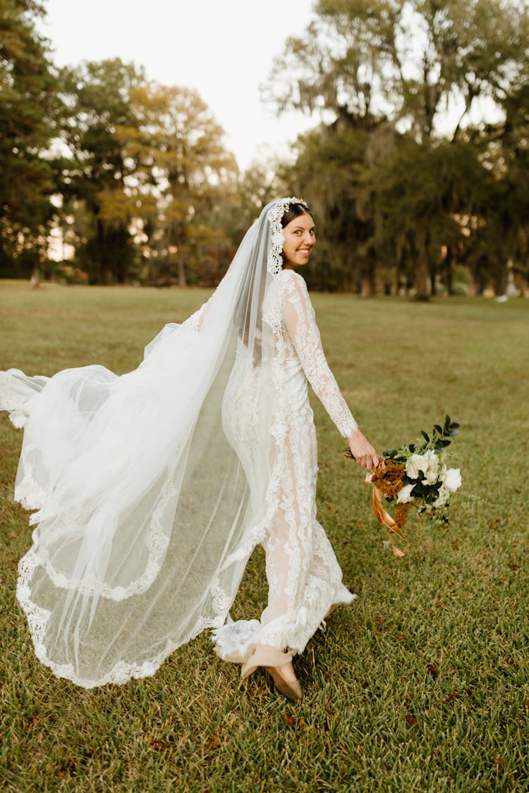 Bride Running In A Park And Looking Behind Her