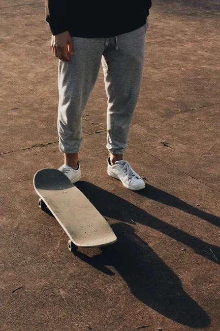 Bas de jogging gris retombant sur des sneakers basses blanches, vue de face