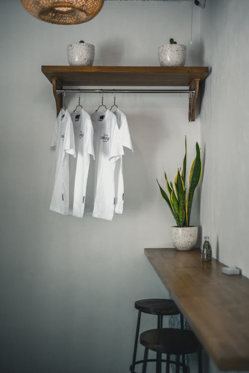 White T-Shirts Hanging on Clothes Rack on Wall