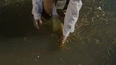 Man in White Shirt and a Name Tag Walking in Water