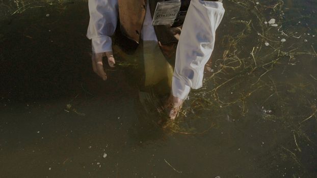 Man in White Shirt and a Name Tag Walking in Water 