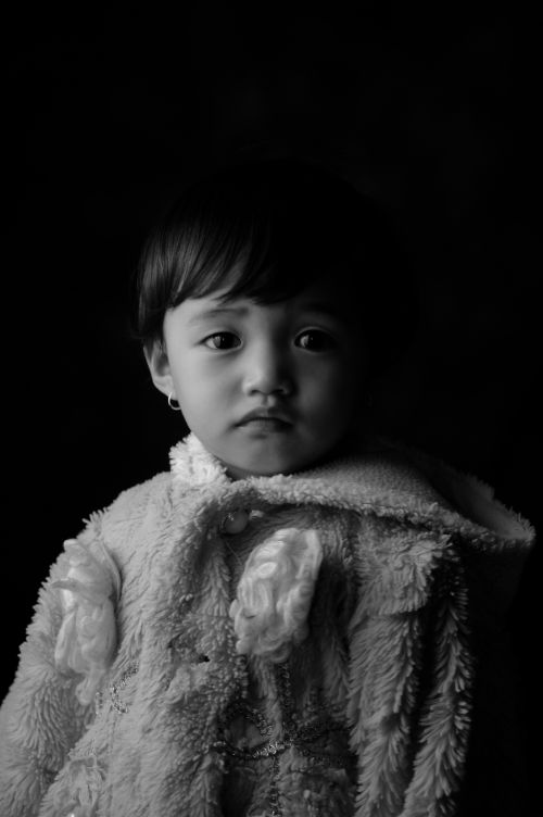 Free Heartwarming black and white portrait of a young child wearing a fleece hoodie in Indonesia. Stock Photo