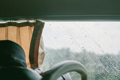 Free Glimpse of a rainy landscape through a car window with raindrops and curtains. Stock Photo