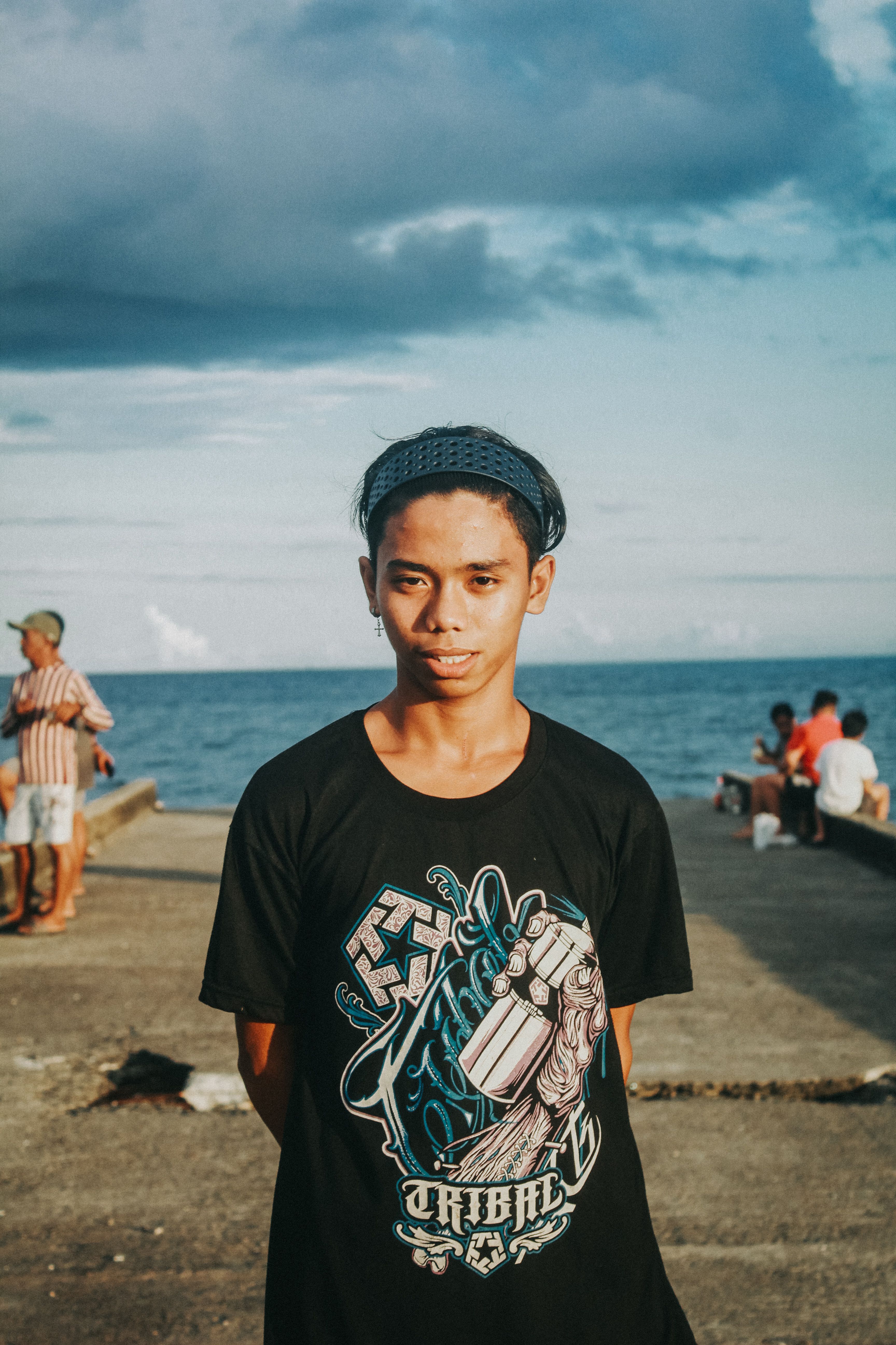 Young male posing on a pier by the sea on a sunny day, exuding a relaxed vibe.