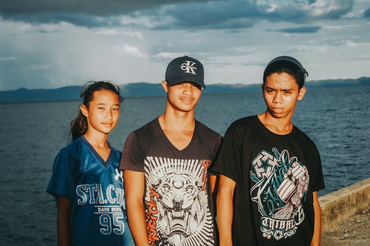 Teenagers Wearing T-Shirts With Graphics Posing By A Sea