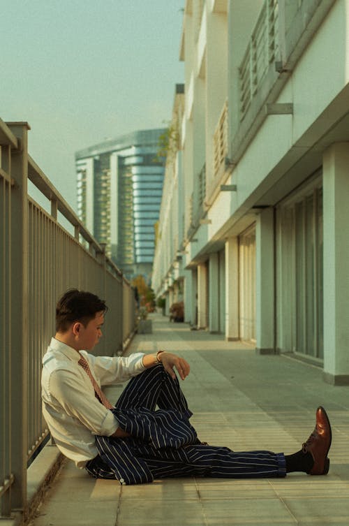 Man Sitting on Balcony Leaning on Railing