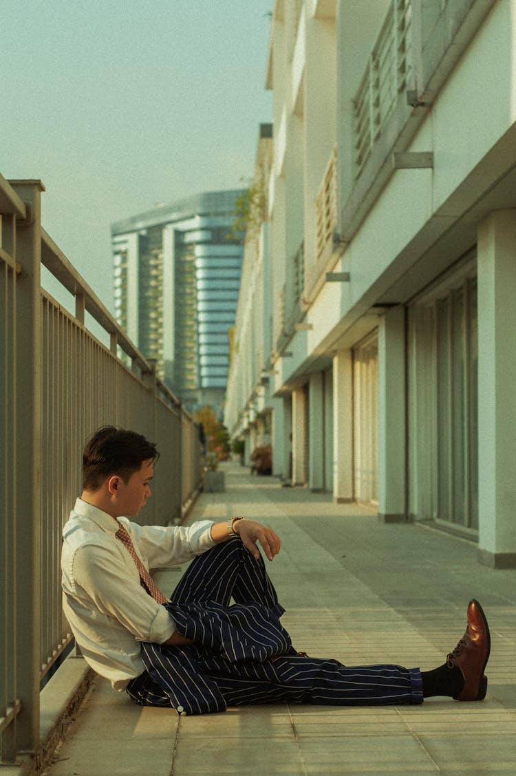 Man Sitting On Balcony Leaning On Railing