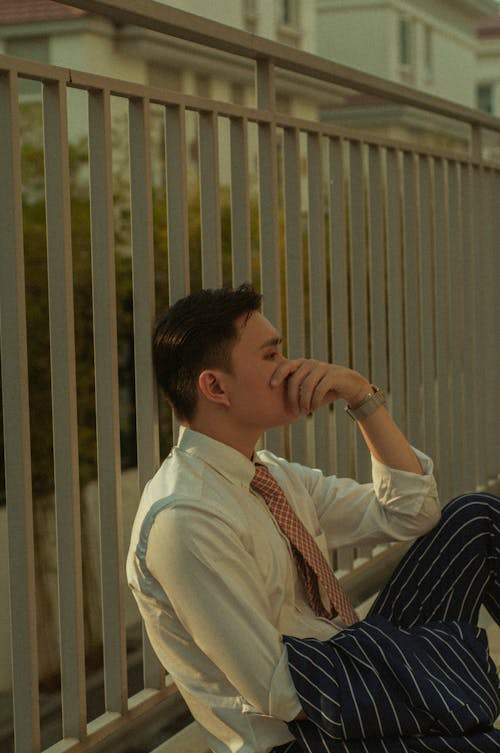 A Man Sitting by a Railing