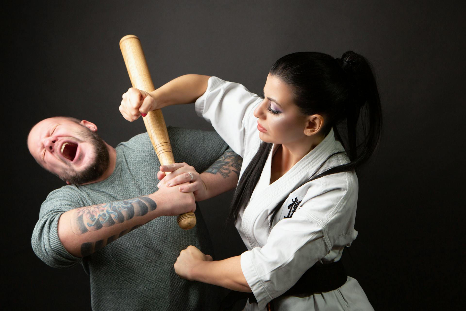 A Woman Punching a Man Holding a Wooden Bat