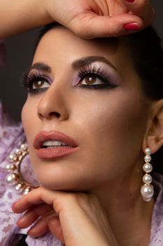 Close-up portrait of a glamorous woman showcasing pearl earrings and makeup.