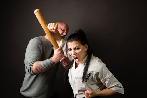 Free Woman in Karate Uniform Punching a Man in Green Sweater Stock Photo