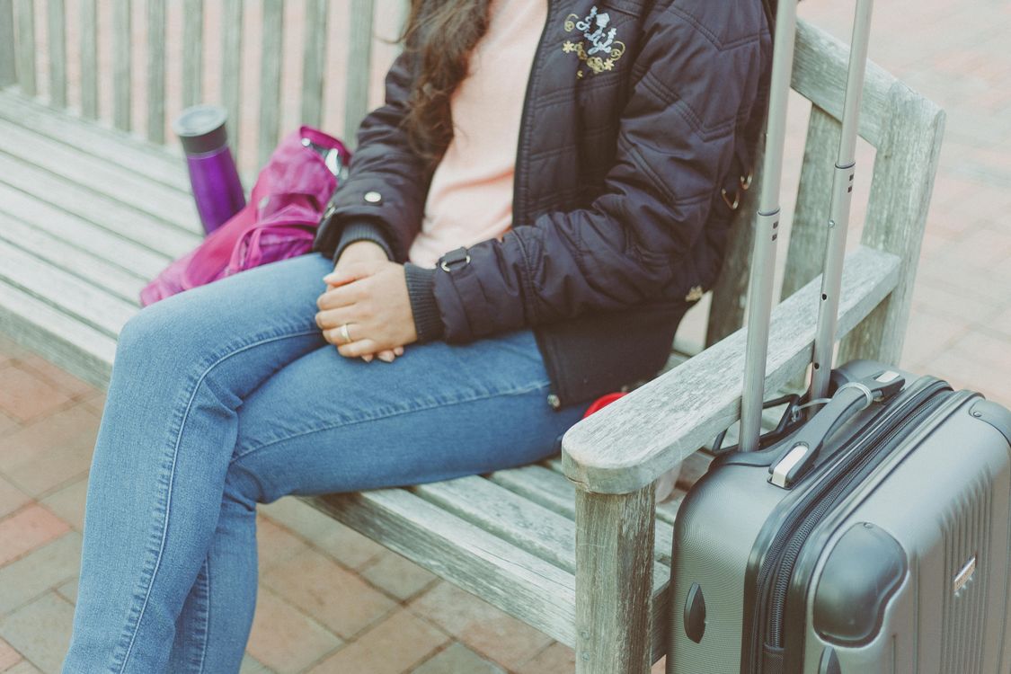 Free Casual woman sitting on bench with luggage in Columbia, MD. Stock Photo