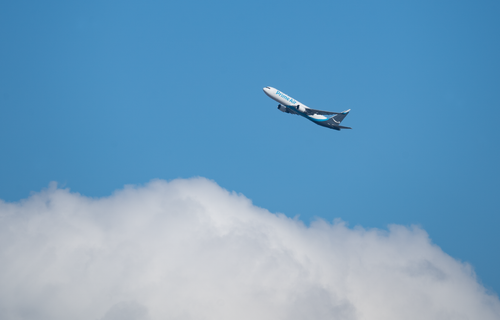 Free A commercial airplane from Prime Air flying high above fluffy clouds against a clear blue sky. Stock Photo