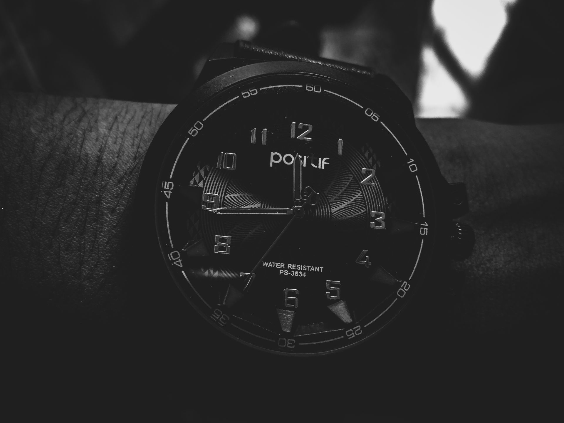 Monochrome photo of an analog wristwatch showing detailed numbers and time.