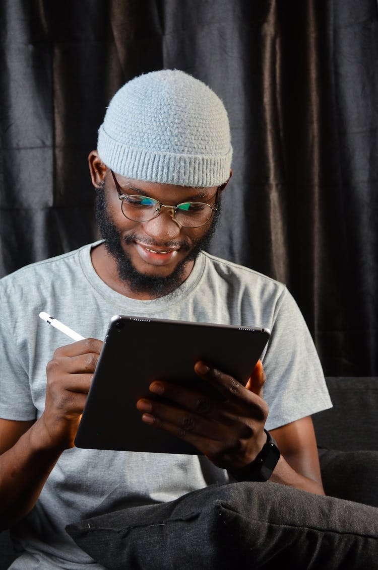 Portrait Of Man In Hat And Glasses Using Tablet