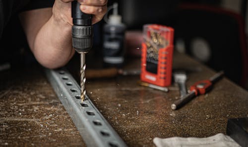 Person Using a Hand Drill on Metal