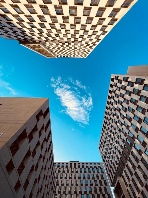 Free Perspective view of high-rise buildings framing a blue sky with clouds. Stock Photo