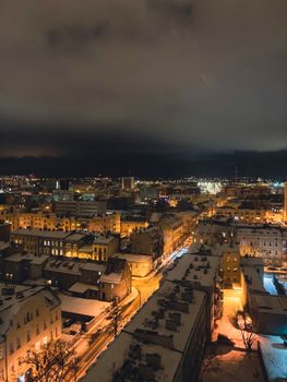 Scenic aerial view of Bydgoszcz, Poland at night with snow-covered rooftops and city lights.