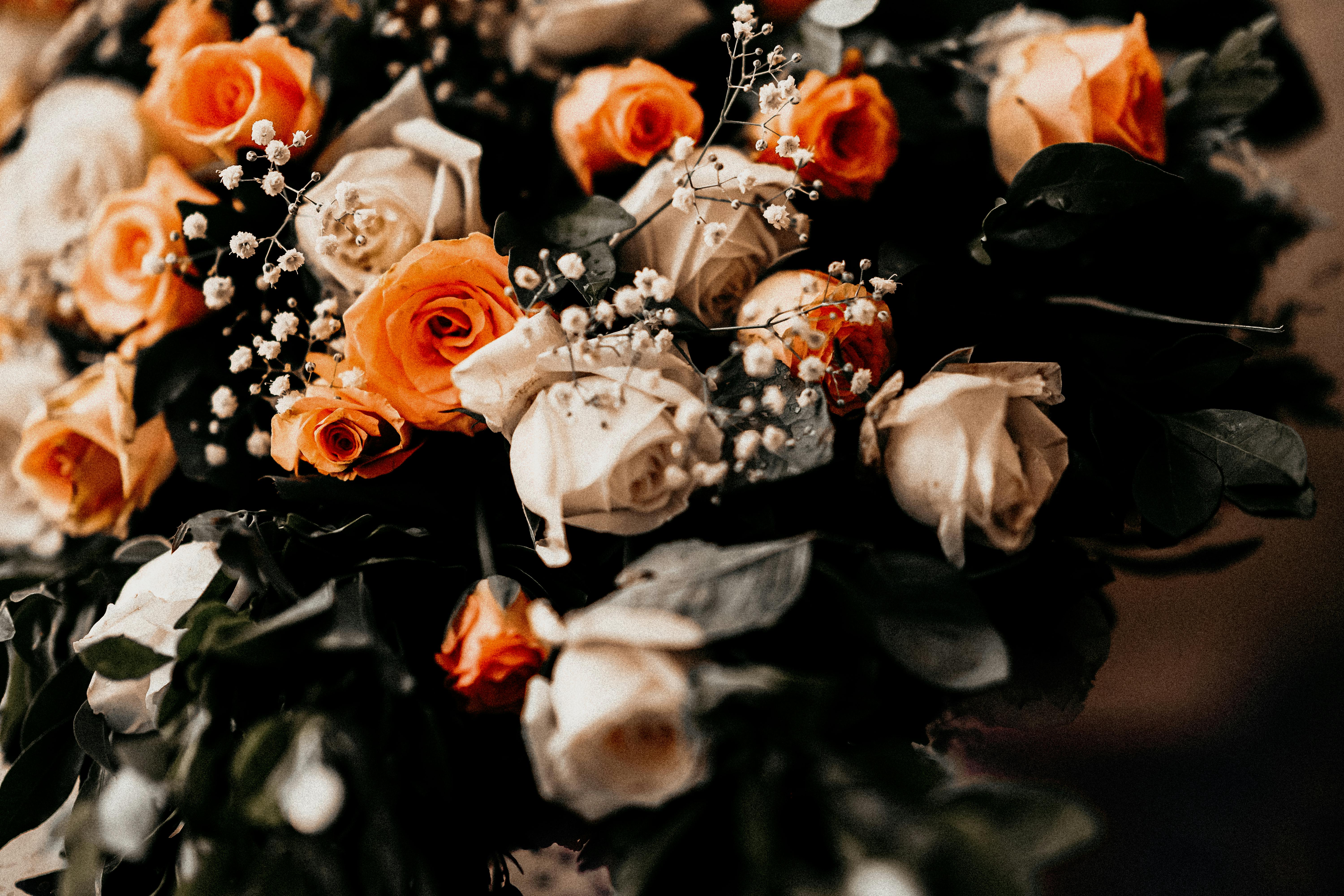A stunning close-up of an elegant bouquet featuring orange and cream roses with delicate foliage.