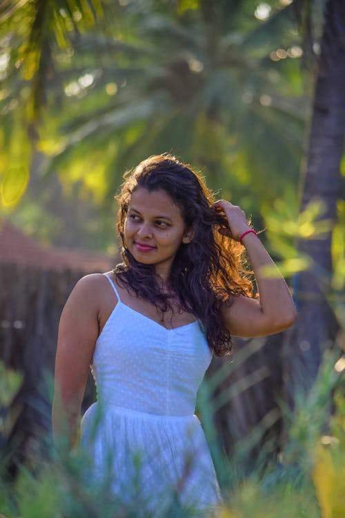 A Woman in White Dress Standing Near Green Plants