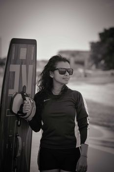 Monochrome portrait of a woman in activewear holding a wakeboard on a beach in Kalpitiya, Sri Lanka.
