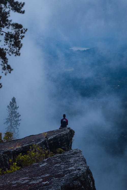 Man Sitting on Edge of Rock Formation