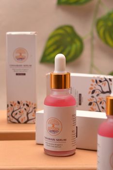 Stylish presentation of Cinnabari serum bottles with vibrant packaging and a touch of greenery.