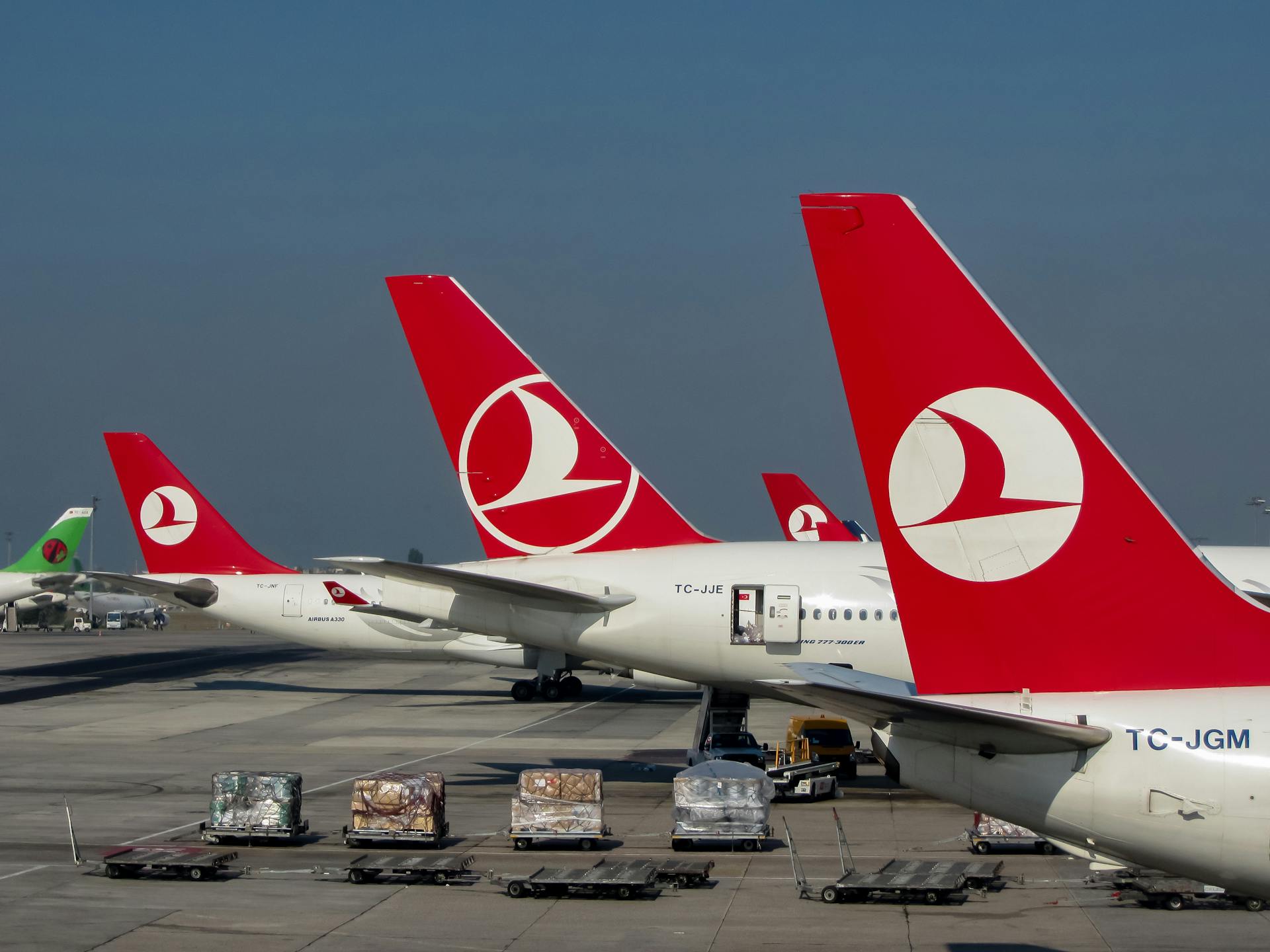 Turkish Airlines aircraft on the tarmac at Istanbul Airport, showcasing vibrant red tails under clear skies.