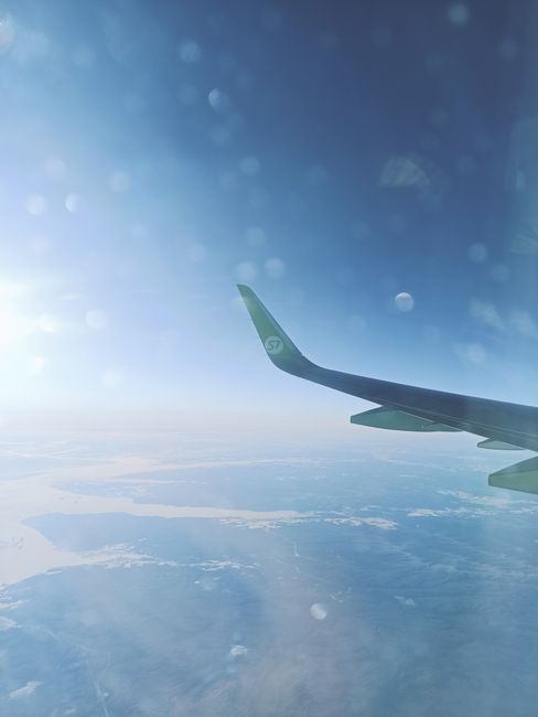 Scenic view of airplane wing flying over the clouds during the day.