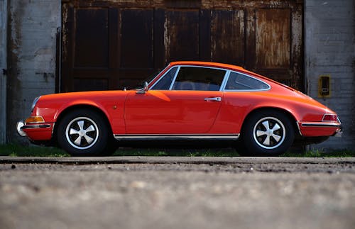 Free Orange Fastback Car Near Wall Stock Photo